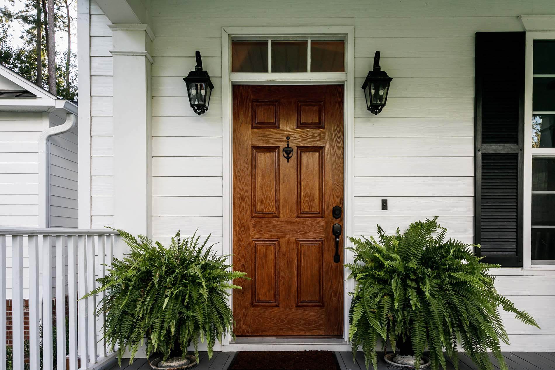 brown wooden door with plants outside and white walls